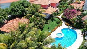 An aerial view of a resort with a swimming pool surrounded by lush greenery and palm trees.