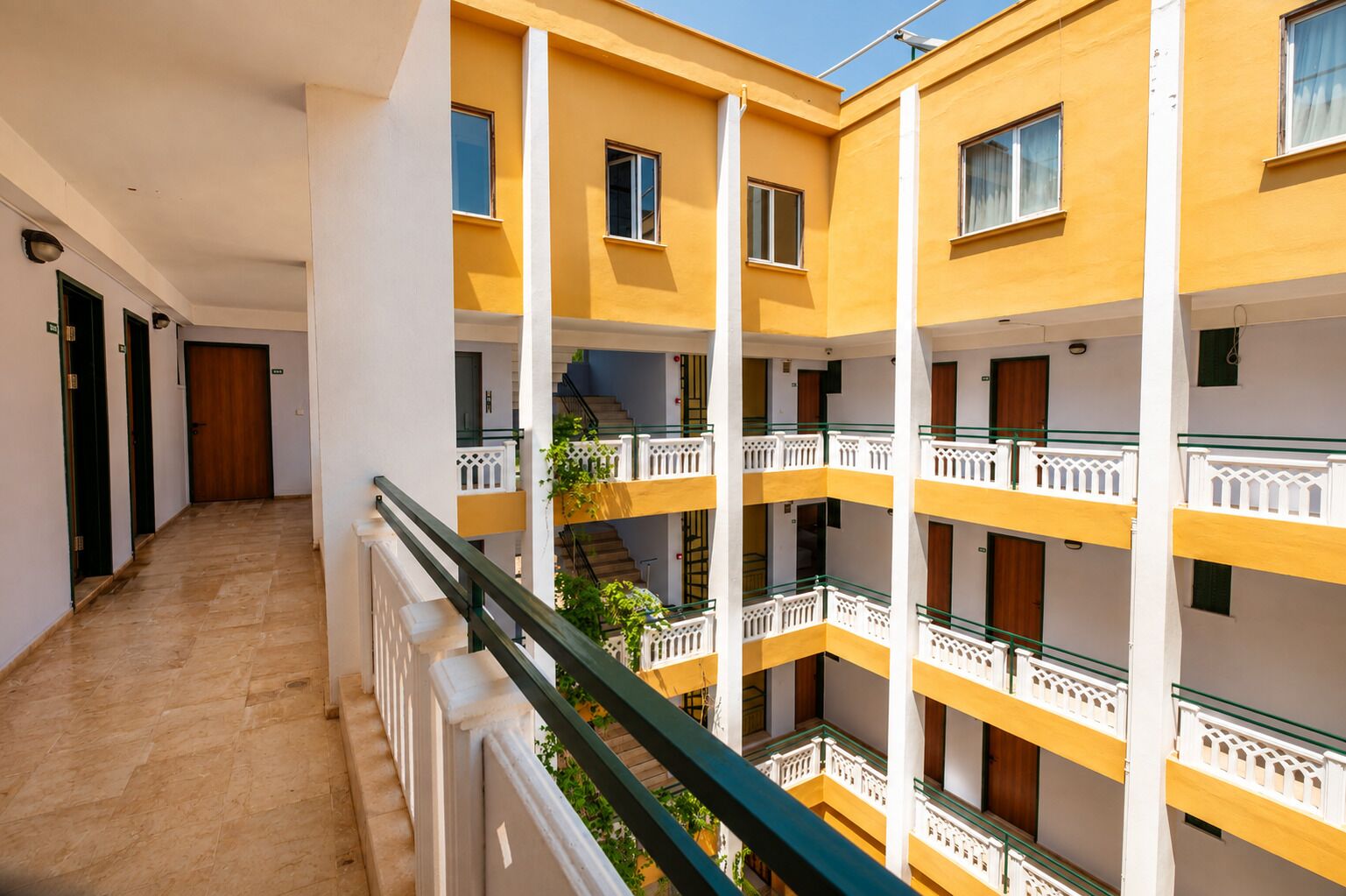 Un edificio de varios pisos con balcones, una escalera central y un pasillo.