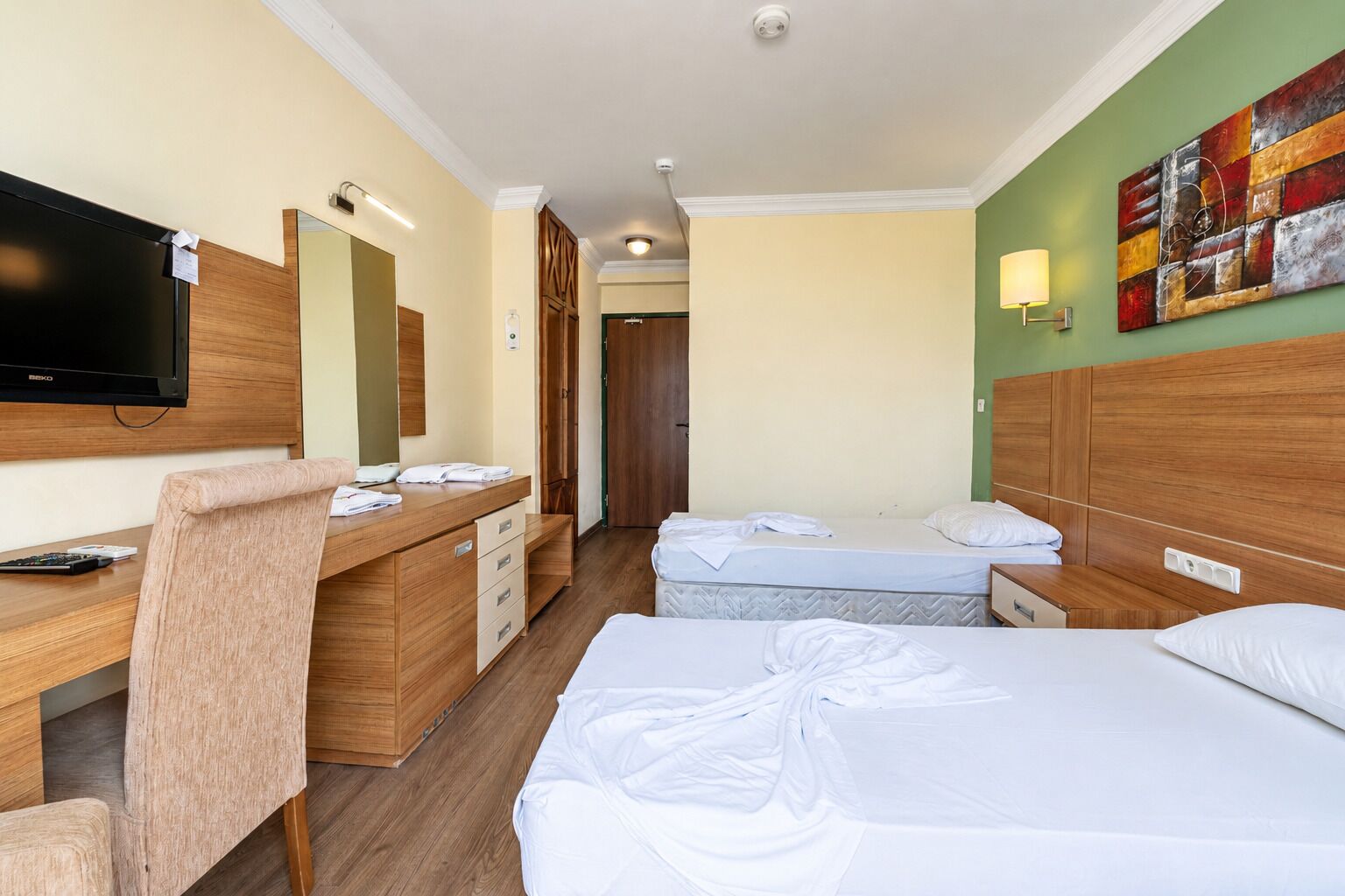 Una habitación de hotel con cama, escritorio, silla, televisor y baño.