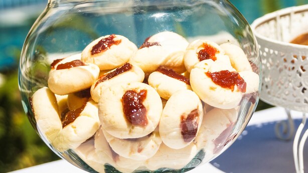 A glass bowl filled with pastries on a table outdoors.