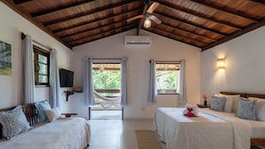 A bedroom with two beds, a ceiling fan, an air conditioning unit, a TV, and a hammock.