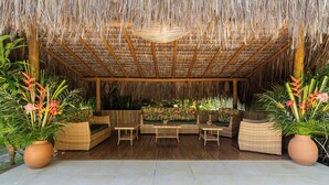 A covered outdoor seating area with wicker furniture and potted plants.