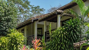 A pool surrounded by lush tropical plants and a building with a tiled roof.