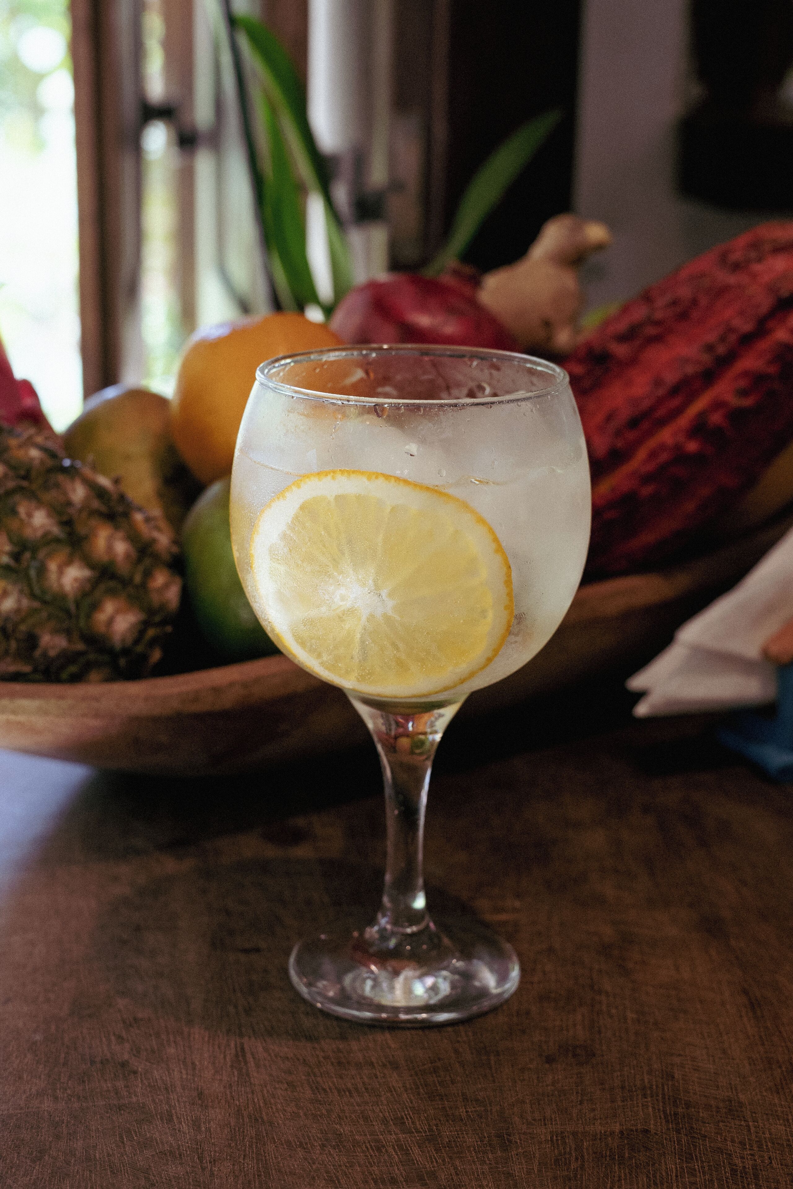 A glass of iced beverage with a lemon slice on a wooden table.