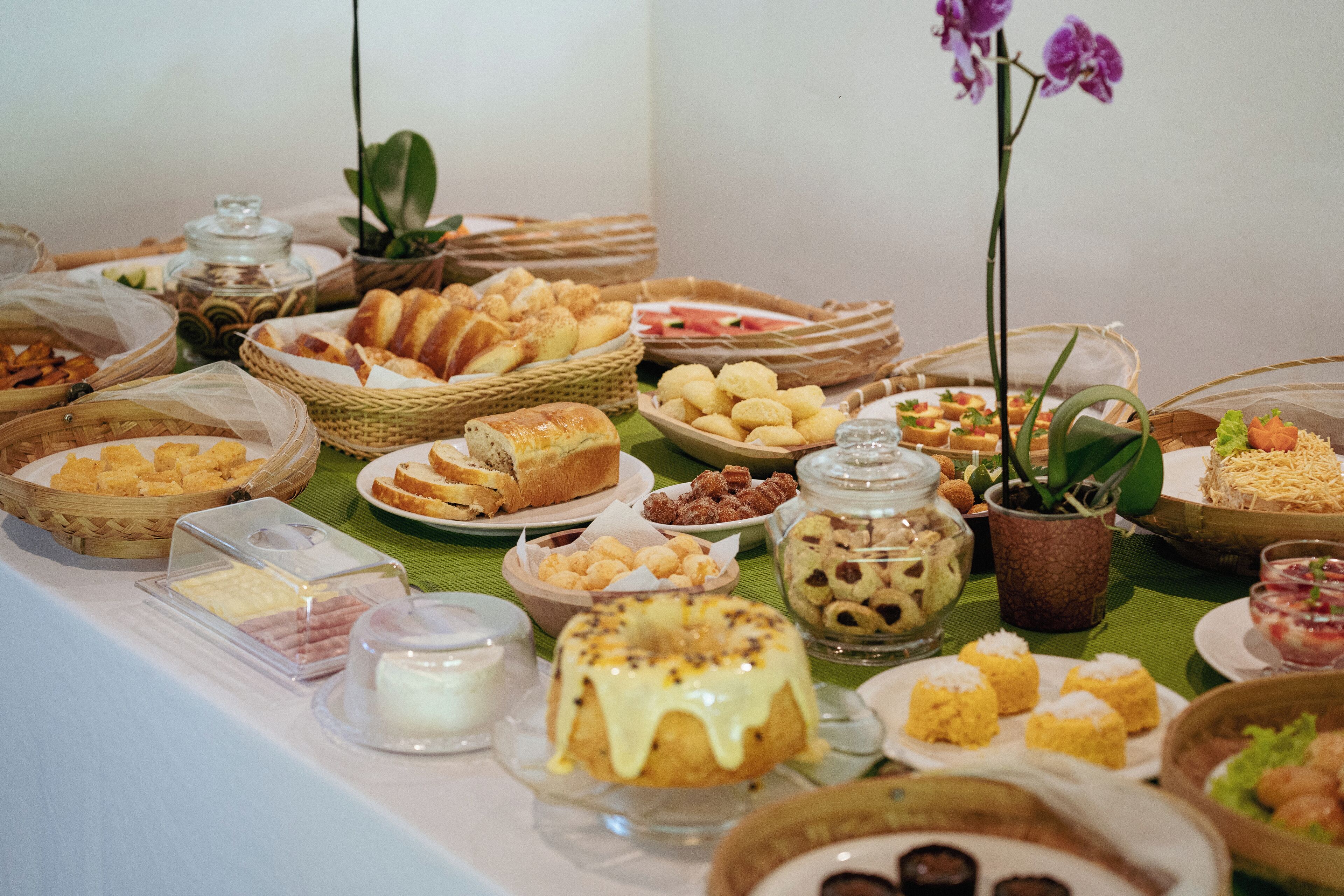 A buffet table with various food items and a potted orchid.