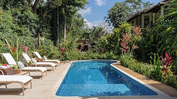 Una piscina al aire libre, sombrillas, tumbonas