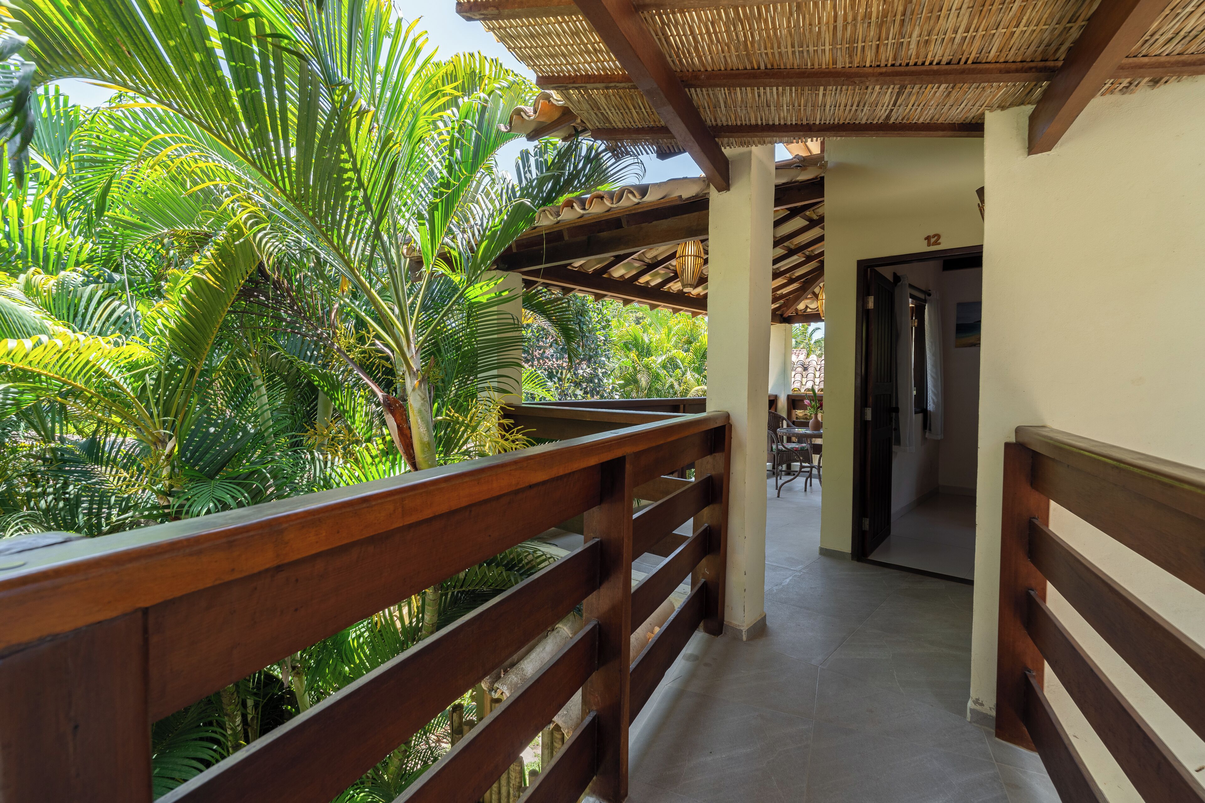A wooden balcony with a view of lush tropical plants.