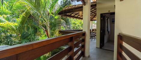 A wooden balcony with a view of lush tropical plants.