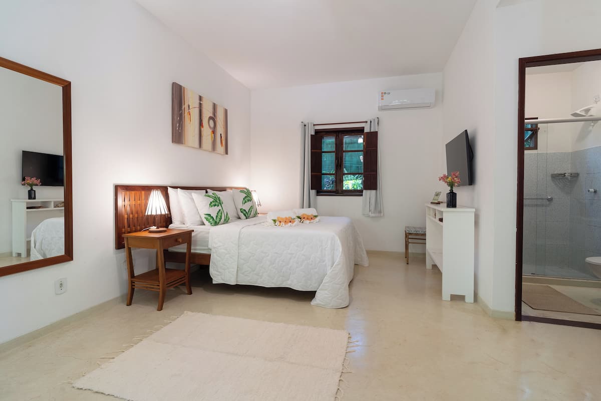 A bedroom with a bed, bedside table, lamp, and a window with curtains.