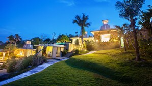 A modern house with a well-maintained lawn, a staircase leading to the entrance, and a clear sky at dusk. - Noah Villa and Chapel (Ungasan)