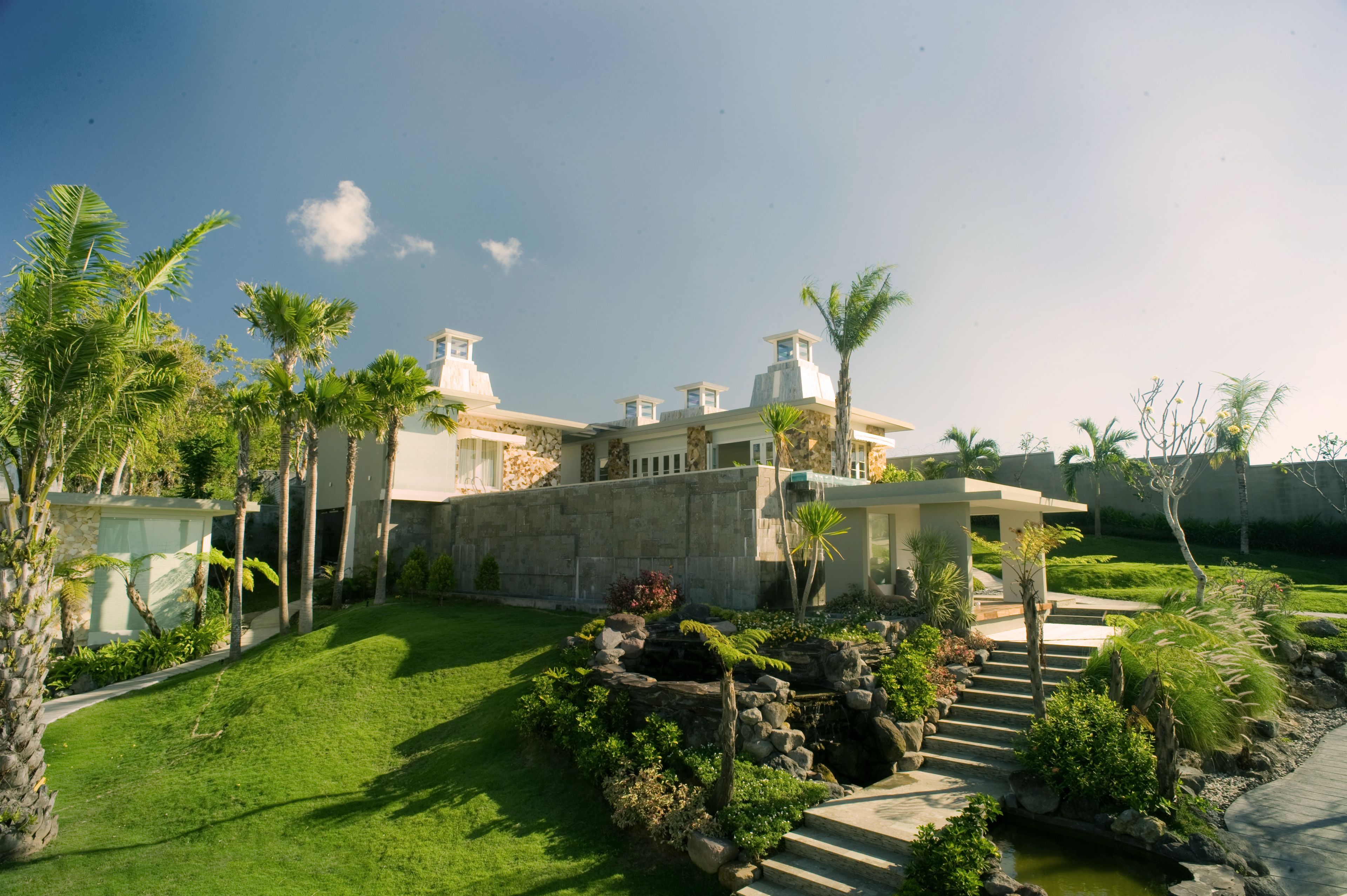 A modern house with a well-maintained garden, stone walls, and a small pond.