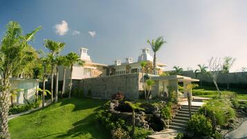 A modern house with a well-maintained garden, stone walls, and a small pond.