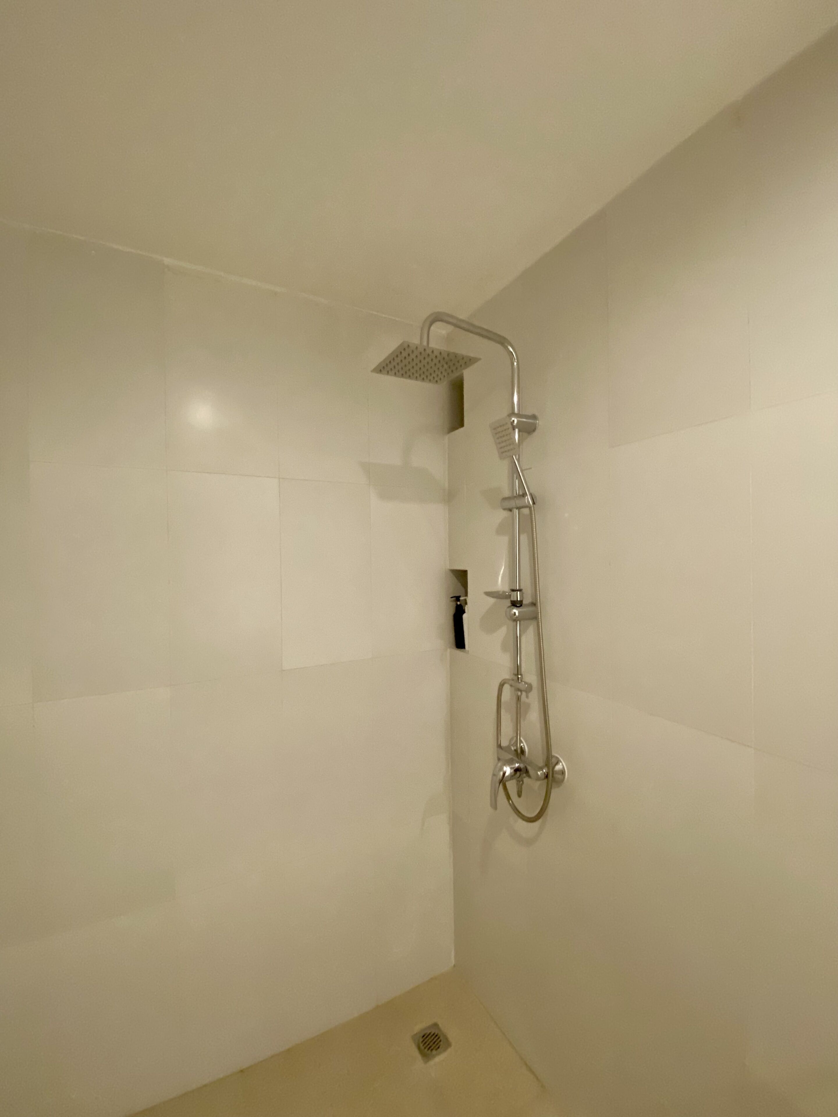 Ein Badezimmer mit Dusche, gefliesten Wänden und einem Abfluss.
