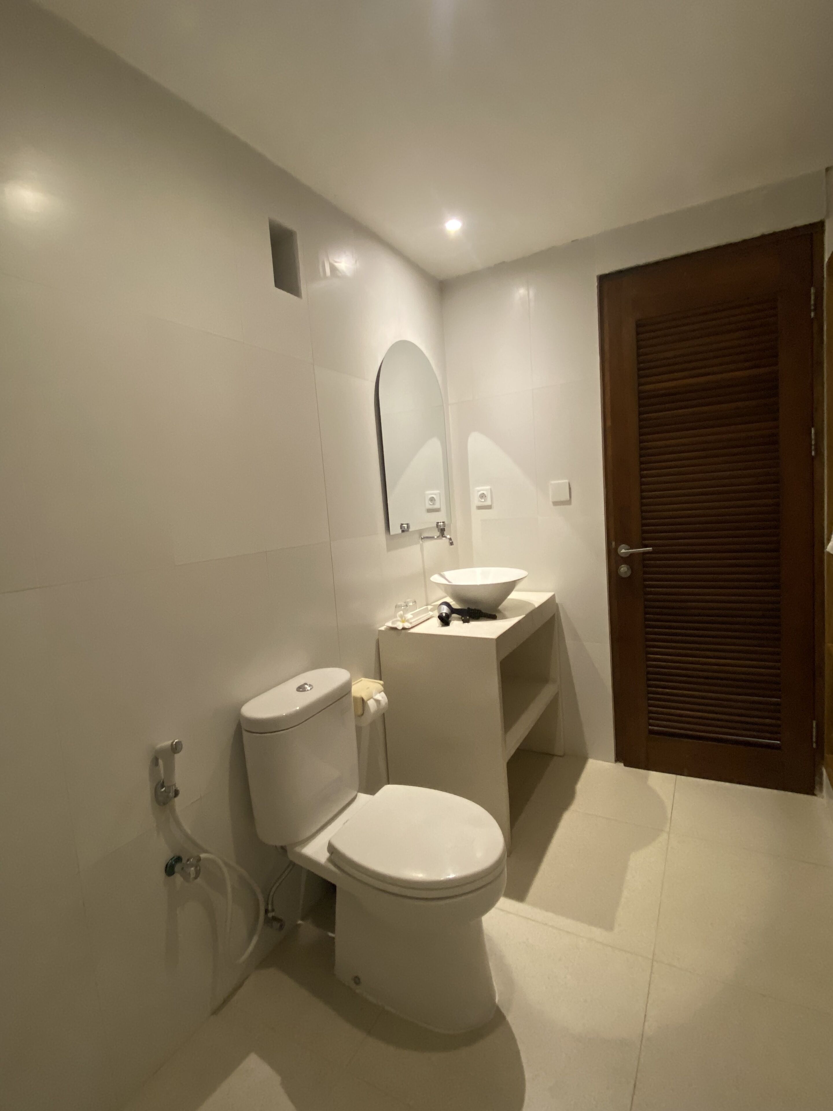 Un baño moderno con inodoro, lavamanos y espejo.