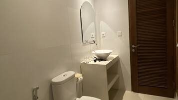 Un baño moderno con inodoro, lavamanos y espejo.