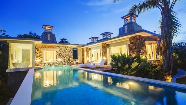 A modern villa with a swimming pool, stone walls, and two lighted towers. - Noah Villa and Chapel (Ungasan)