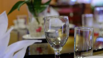 Una mesa de comedor dispuesta con un mantel blanco, una copa de cristal transparente, un plato blanco y una cuchara.