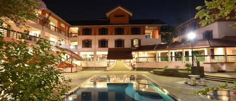 Un edificio grande con piscina, varios balcones y un exterior bien iluminado.