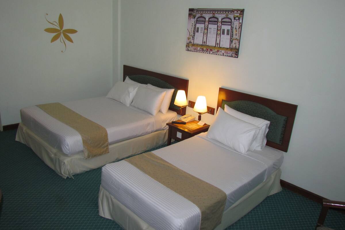 Two single beds with headboards, a nightstand with a lamp, a telephone, and a wall decoration.