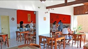 Een restaurant met houten tafels en stoelen, een rode accentmuur en een betegelde vloer.