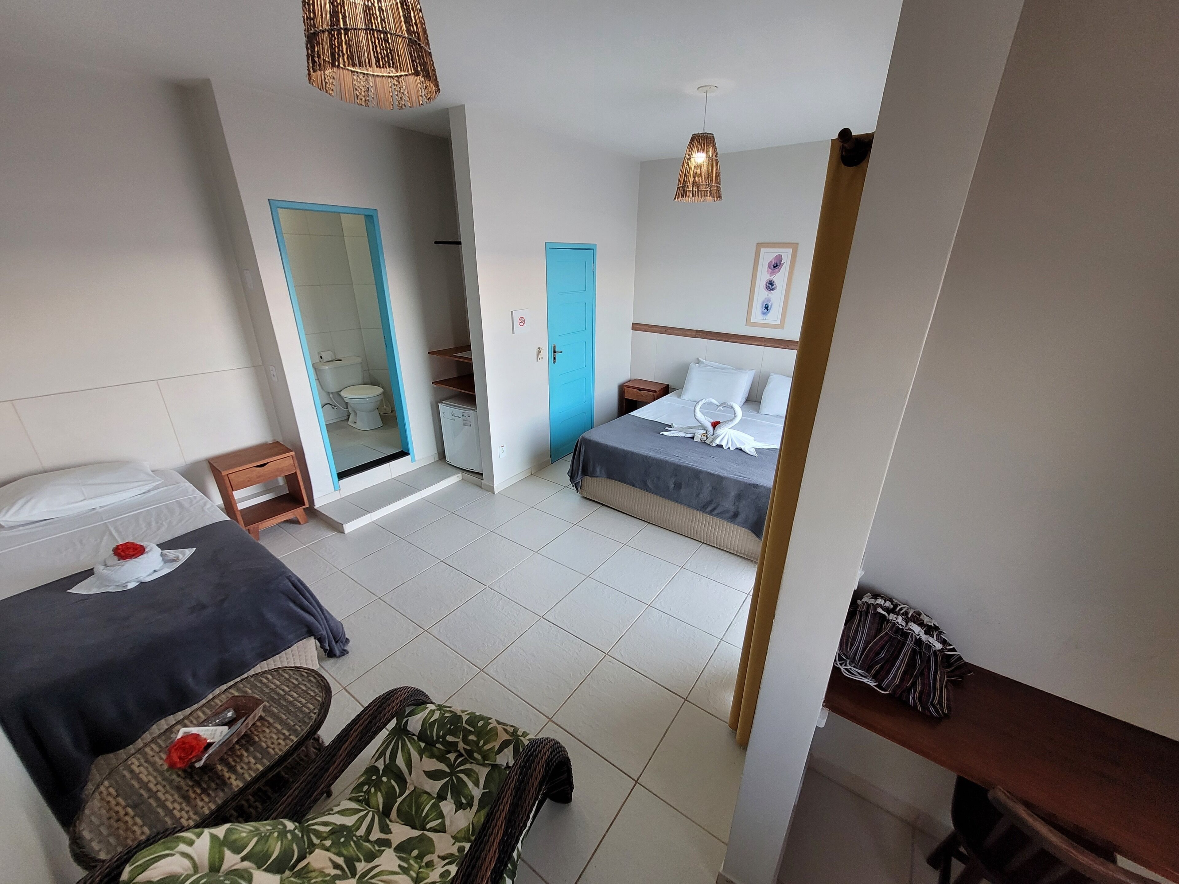 A hotel room with two beds, a bathroom, and a sitting area.