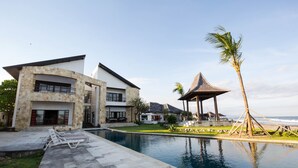 Um resort moderno com piscina, um gazebo e vista para a praia.