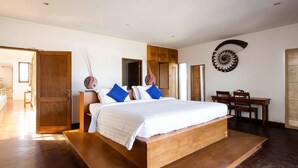 Quarto moderno com uma cama de madeira grande, uma escrivaninha de madeira e uma mesa de jantar.