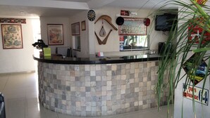 Een receptie met een stenen balie, ingelijste foto's aan de muur, een klok en een bord dat een zwembadzone aangeeft.