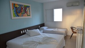 Een hotelkamer met twee bedden, een schilderij aan de muur, een raam en een airconditioning.