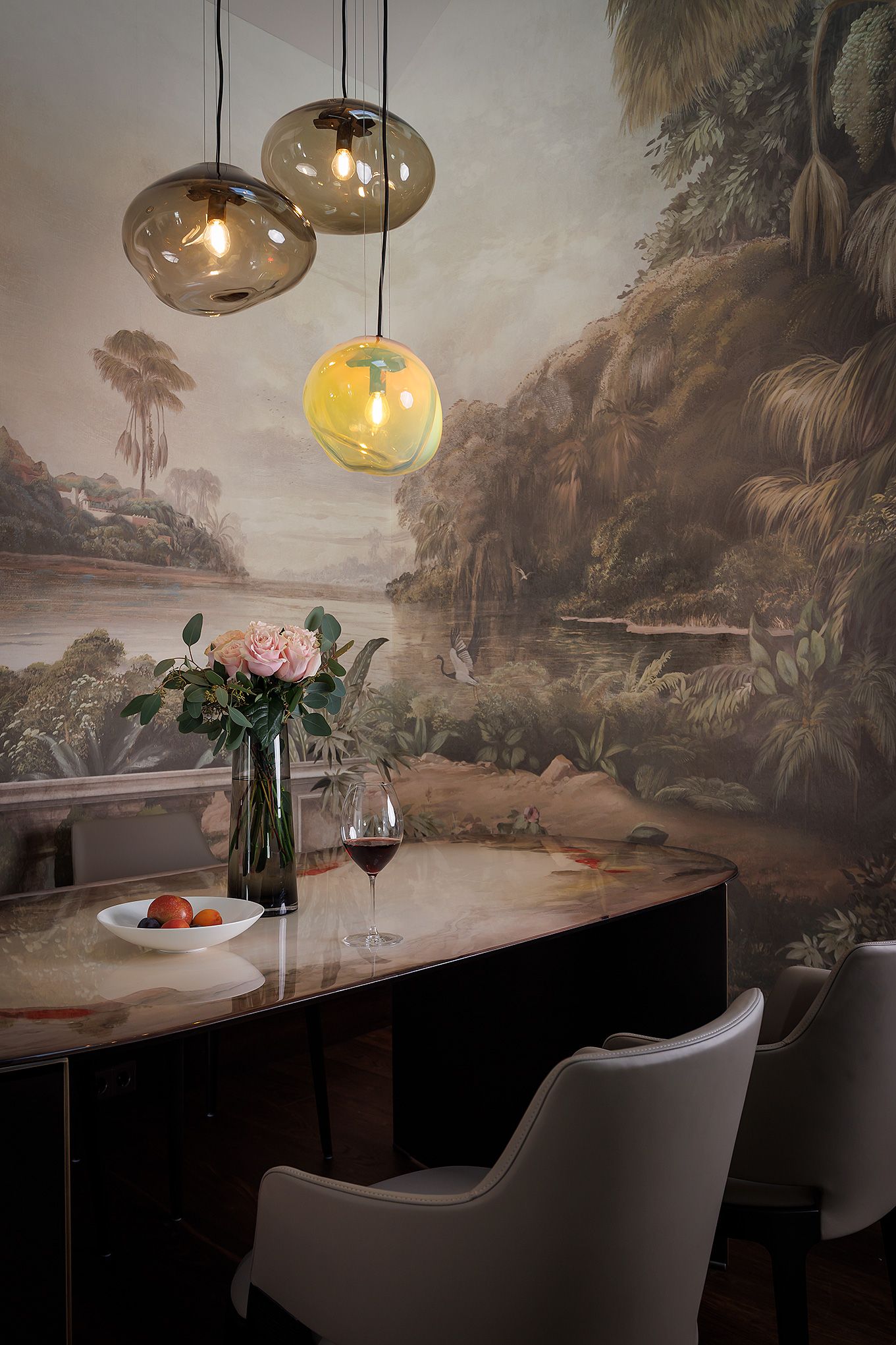 Un'area pranzo con un tavolo apparecchiato per due, un vaso con fiori e un quadro di un paesaggio appeso al muro.