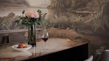 Un'area pranzo con un tavolo apparecchiato per due, un vaso con fiori e un quadro di un paesaggio appeso al muro.