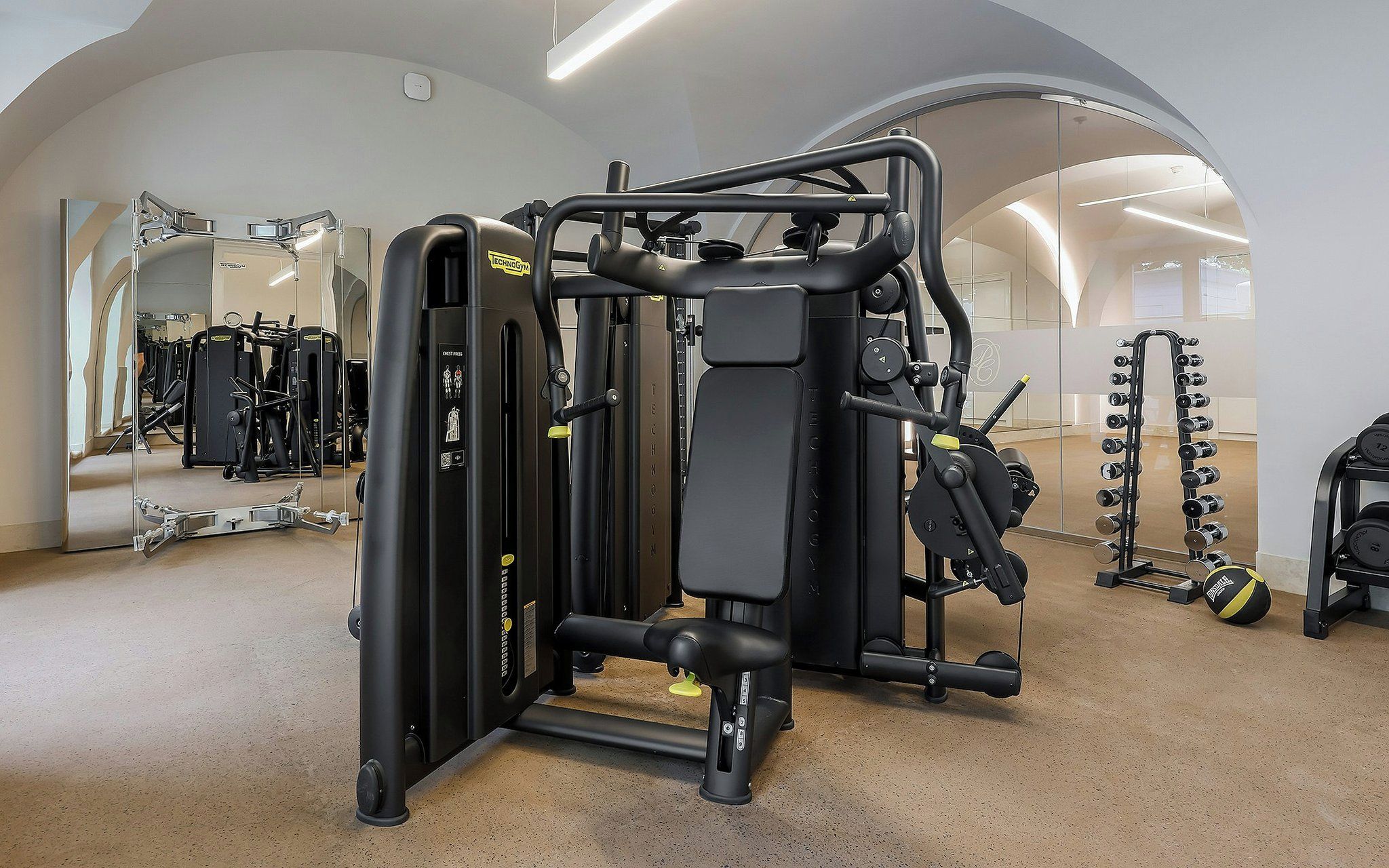 Une salle de sport équipée de divers appareils d’exercice, notamment une machine à développé couché et des haltères.