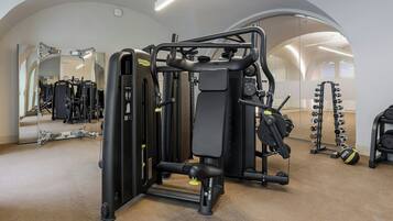 Une salle de sport équipée de divers appareils d’exercice, notamment une machine à développé couché et des haltères.