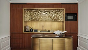 A kitchen with wooden cabinets, a central island, a microwave, and a coffee maker. - Palais Coburg  (Vienna)