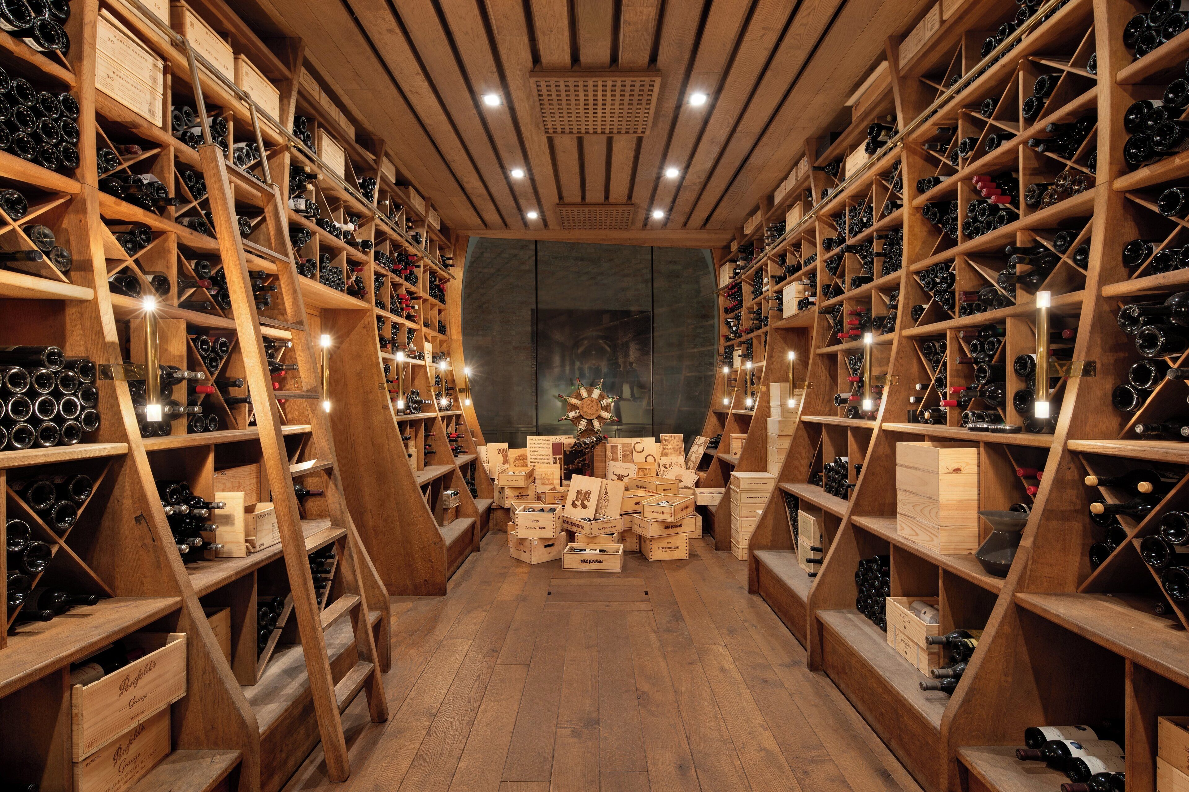 Adega com prateleiras e racks de madeira repletos de garrafas de vinho.