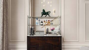 A modern interior with a wooden cabinet, two armchairs, a glass table, and a decorative mirror with a green sculpture.