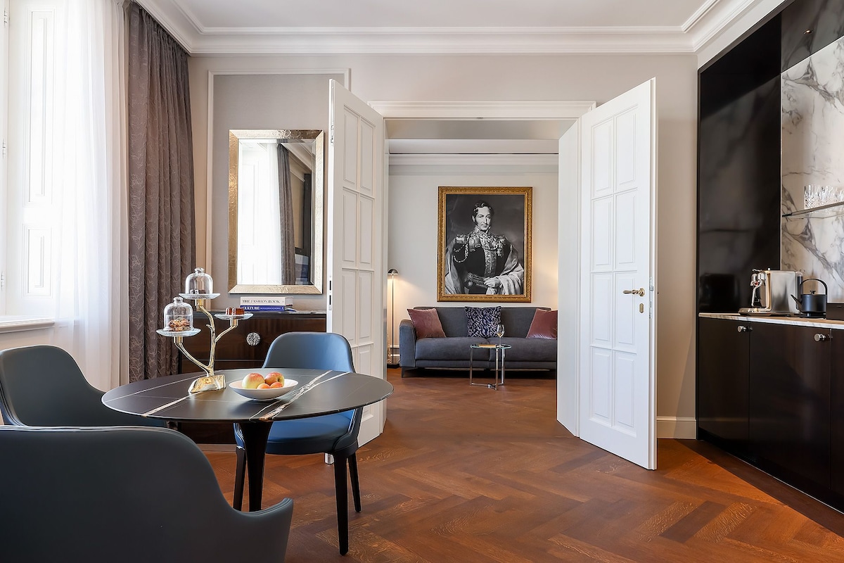 A modern living room with a dining area, a sofa, a coffee table, and a large framed portrait.