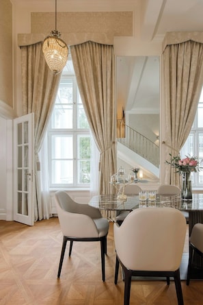 A spacious room with a dining table, two chairs, and a chandelier. - Palais Coburg  (Vienna)
