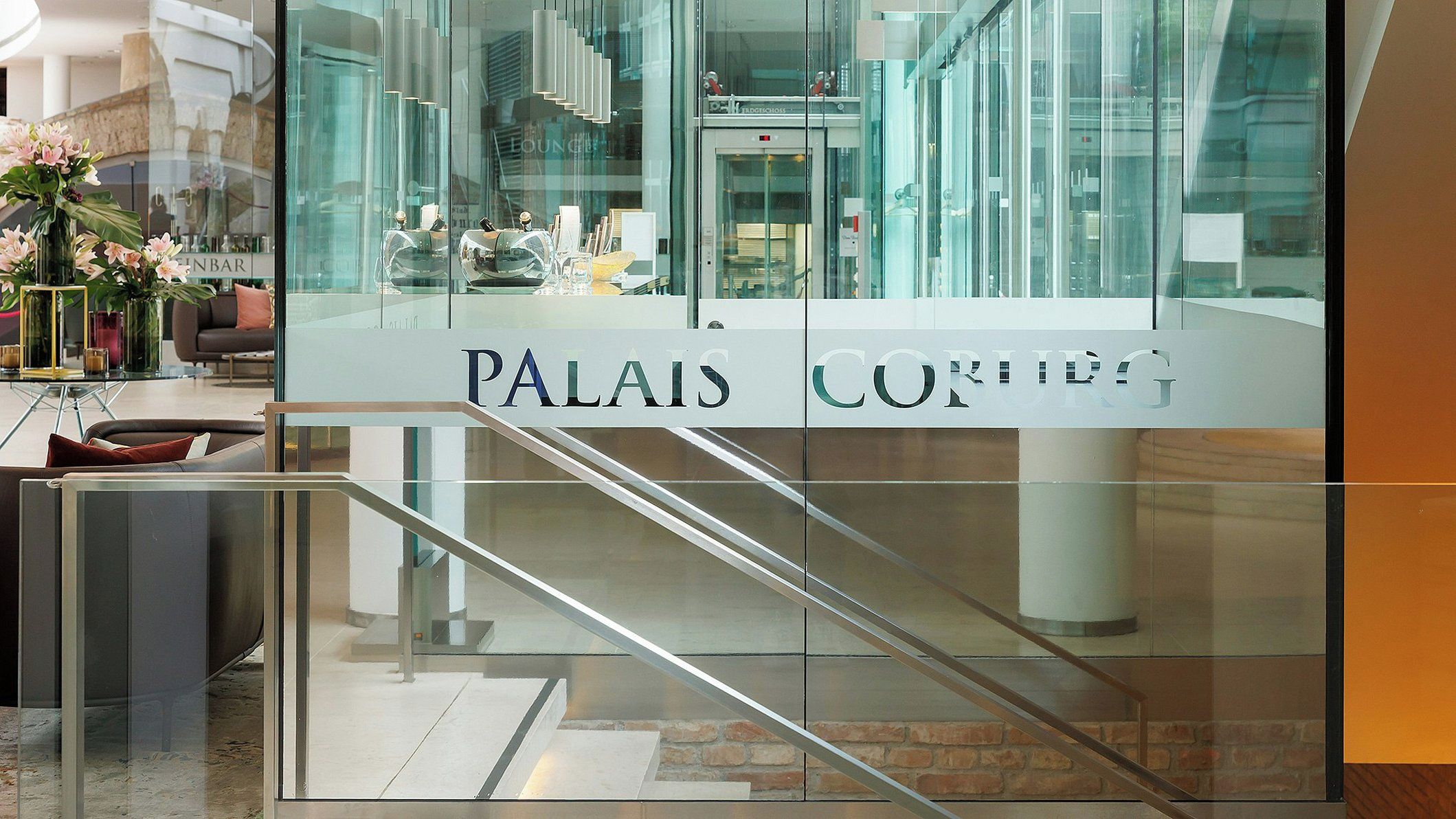 Letrero con vidrio que dice 'PALAIS CORING', con una escalera que conduce a un ascensor.