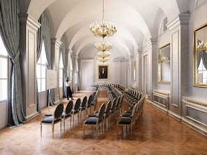 A grand hall with a high arched ceiling, a chandelier, and rows of chairs arranged for a meeting. - Palais Coburg  (Vienna)
