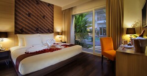 A hotel room with a large bed, a desk with a chair, a window with a view of the outside, and a lamp on the desk. - b Hotel Bali & Spa (Denpasar)