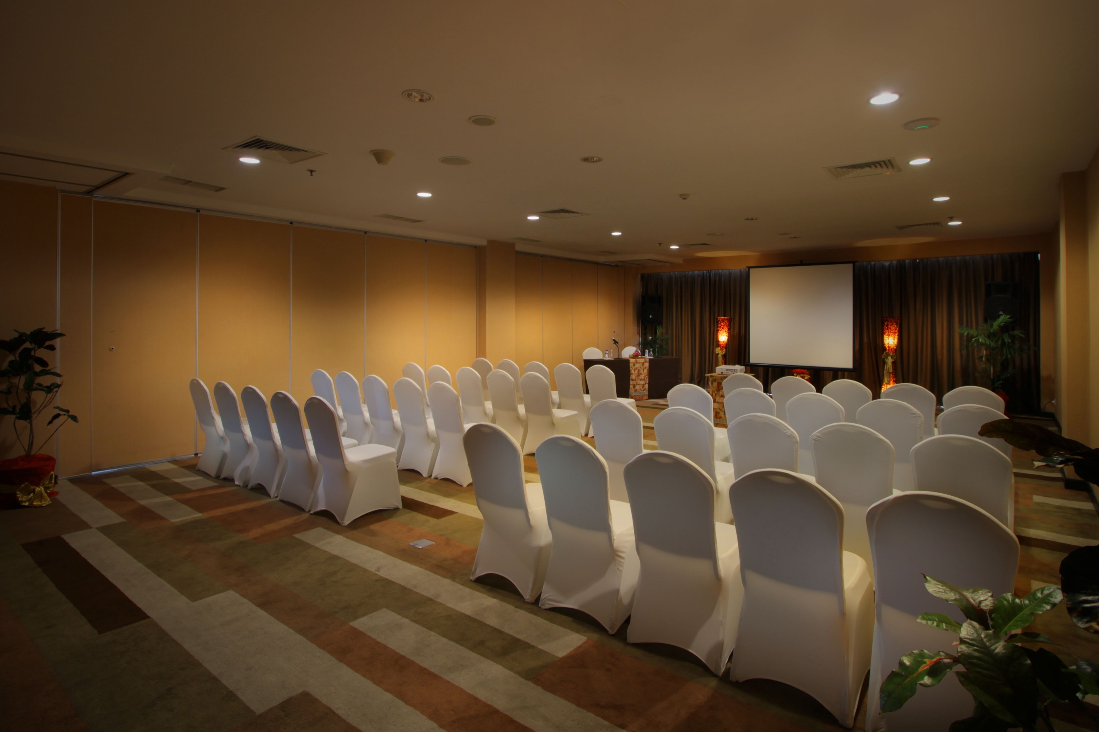 Un salón de conferencias con filas de sillas blancas y un atril al frente.