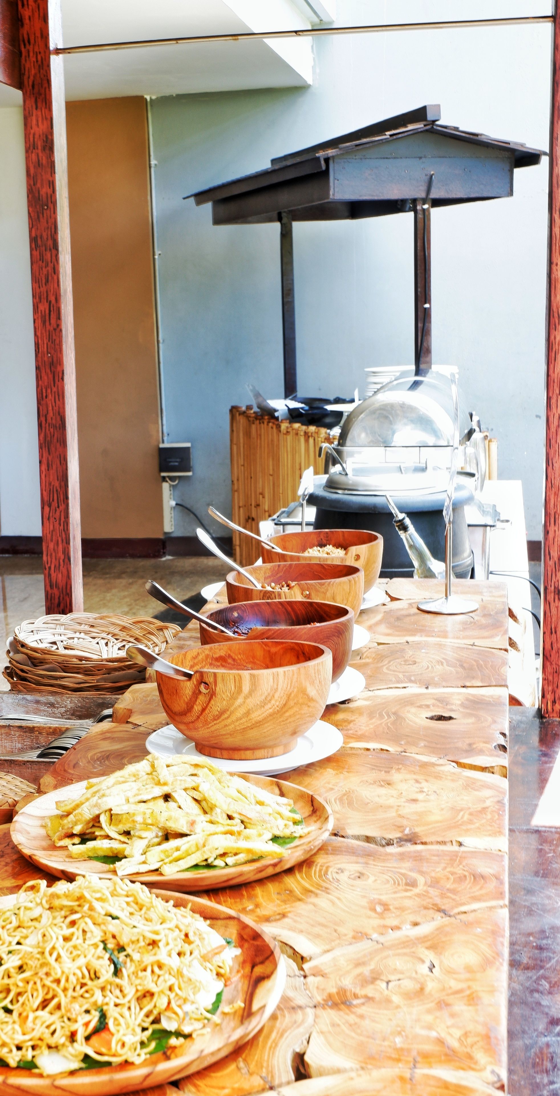 A buffet table with various dishes and wooden bowls.