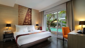Quarto de hotel com uma cama grande, uma escrivaninha e vista para uma piscina.