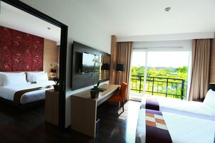 A hotel room with a bed, desk, TV, and a balcony with a view.