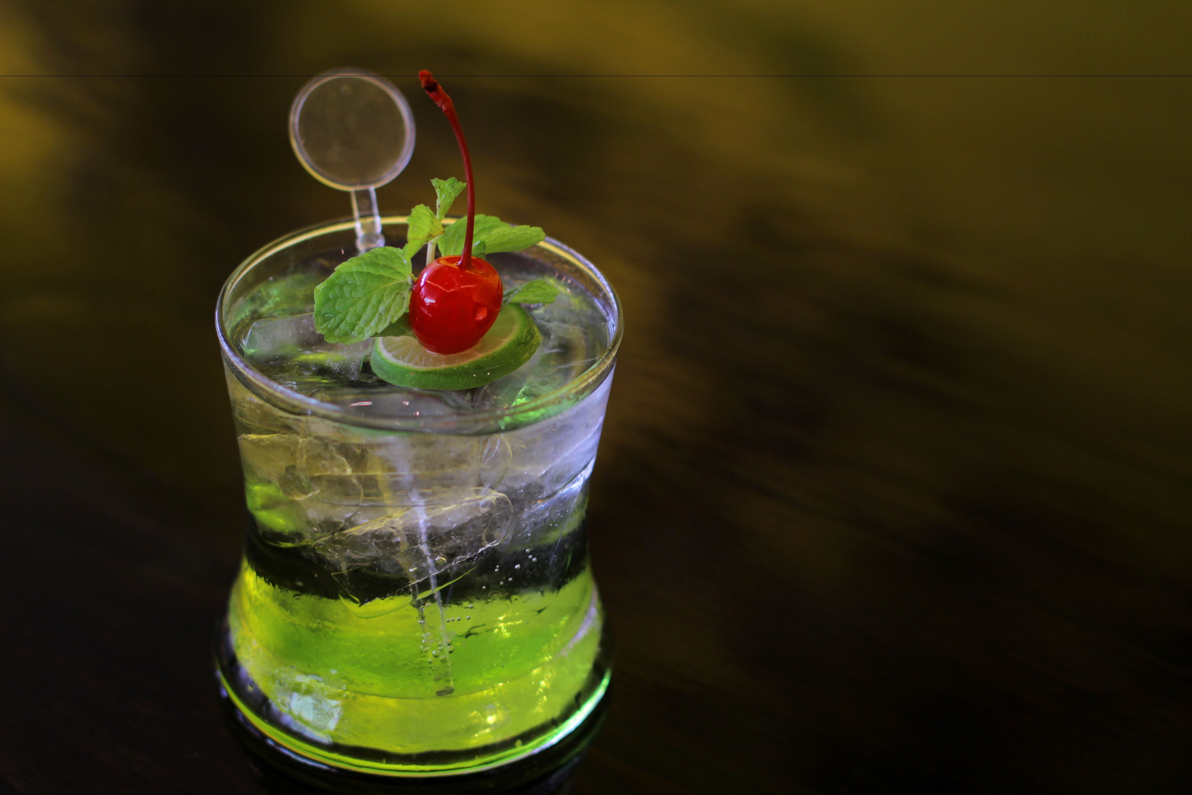 A cocktail with a cherry garnish and mint leaves in a glass.