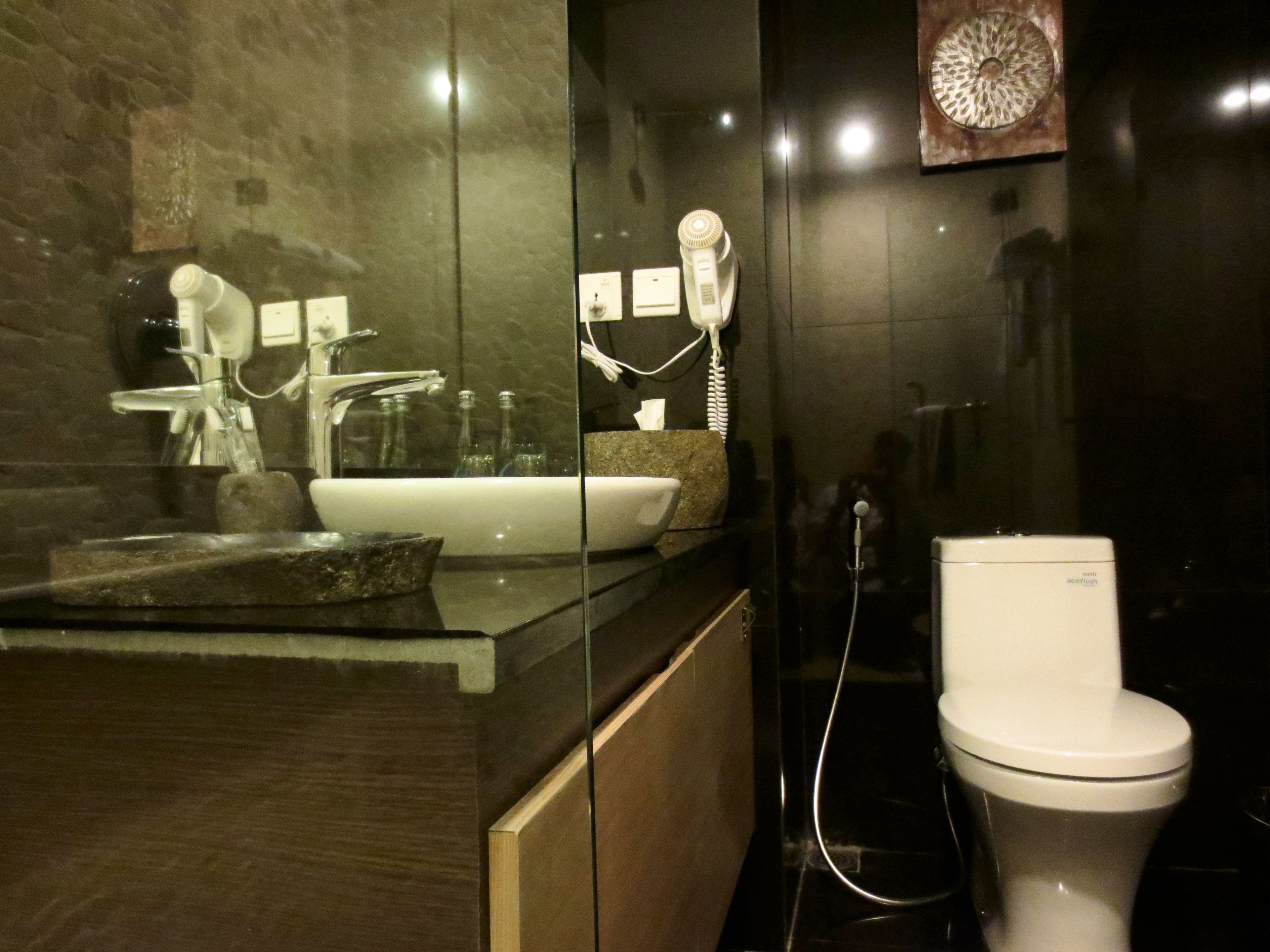 A modern bathroom with a glass shower enclosure, a white sink, and a toilet.