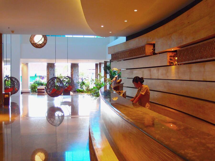 A modern lobby with a polished floor, seating areas with hanging chairs, and a reception desk.
