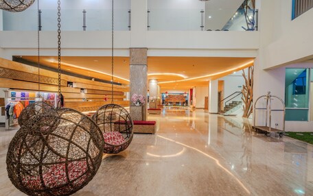 A spacious lobby with hanging spherical seating, a polished marble floor, and a staircase leading to an upper level.