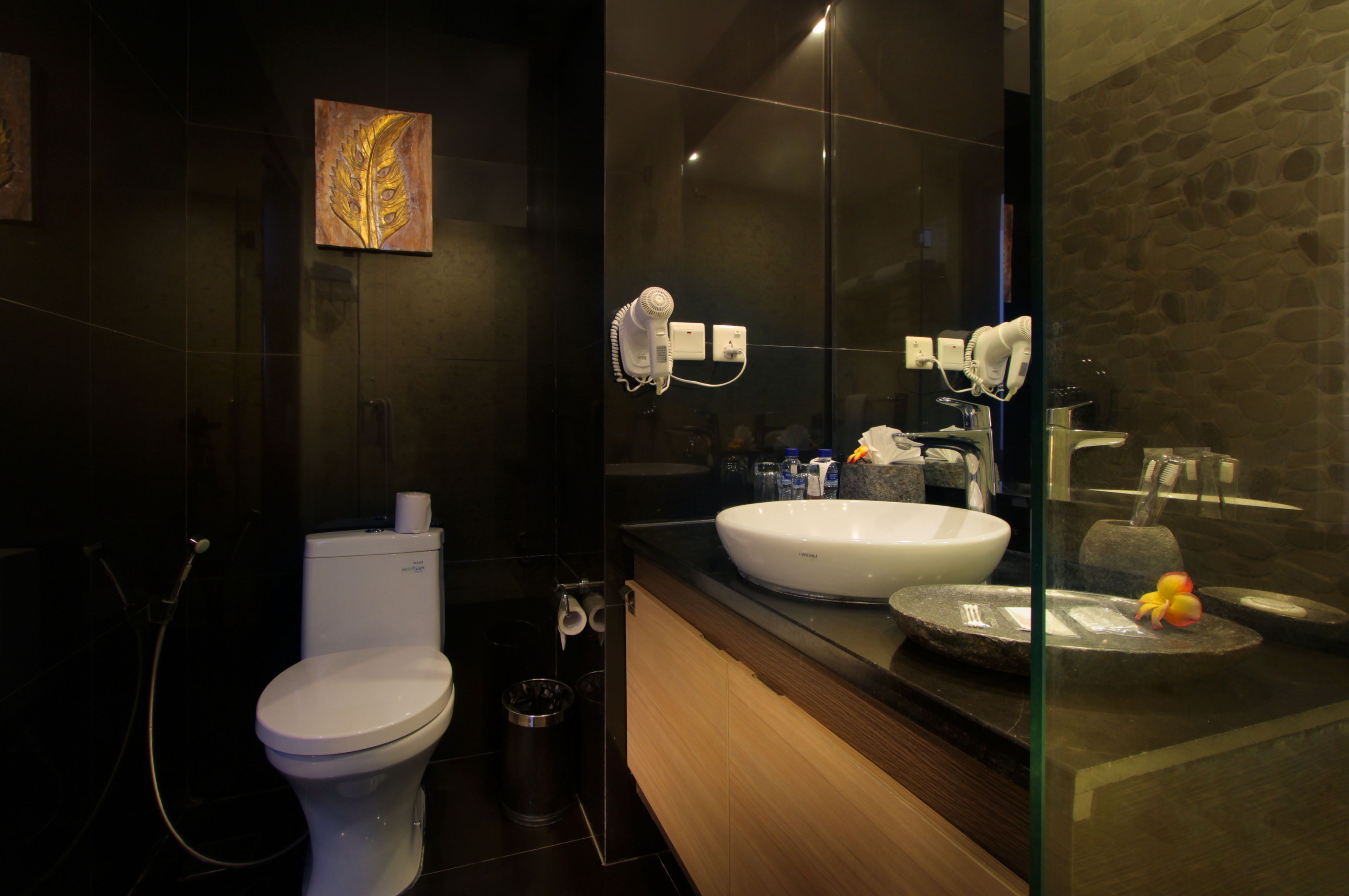 A modern bathroom with a toilet, bidet, and a large sink with a mirror above it.